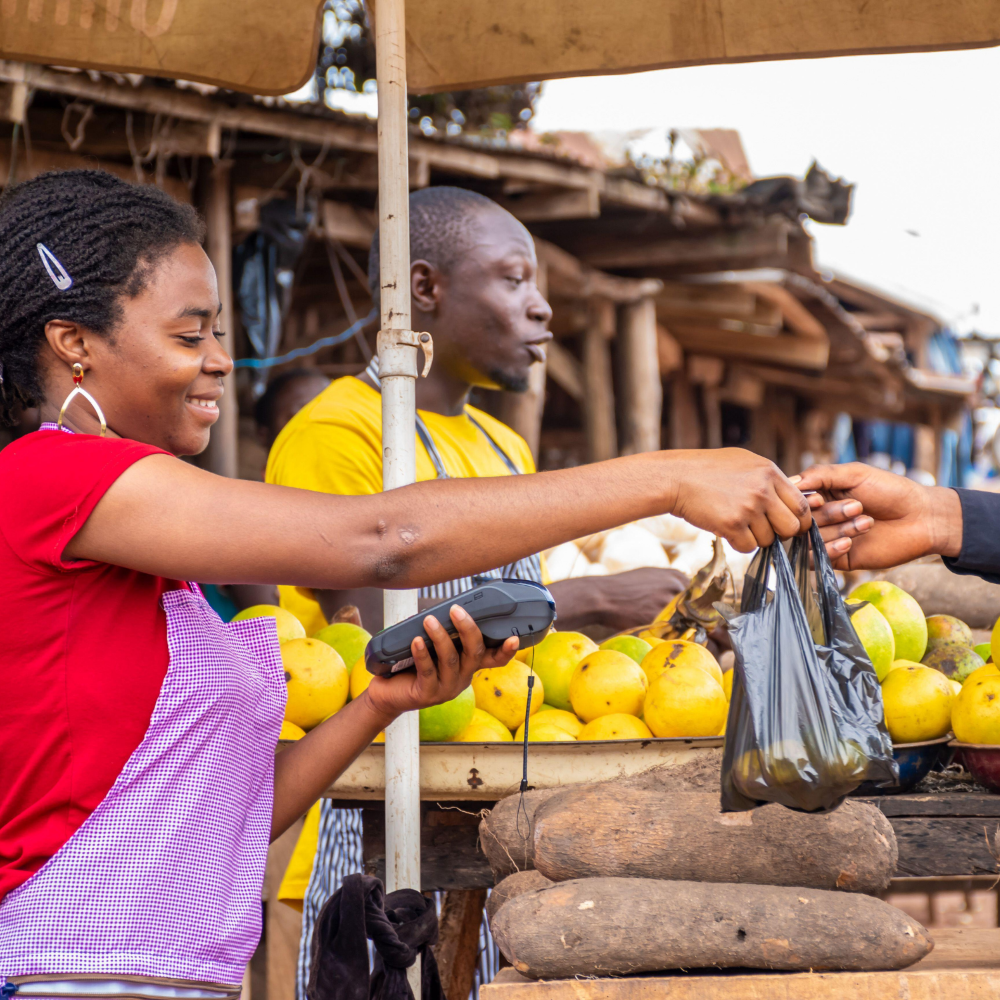 Woman in red shirt selling products in a market.
