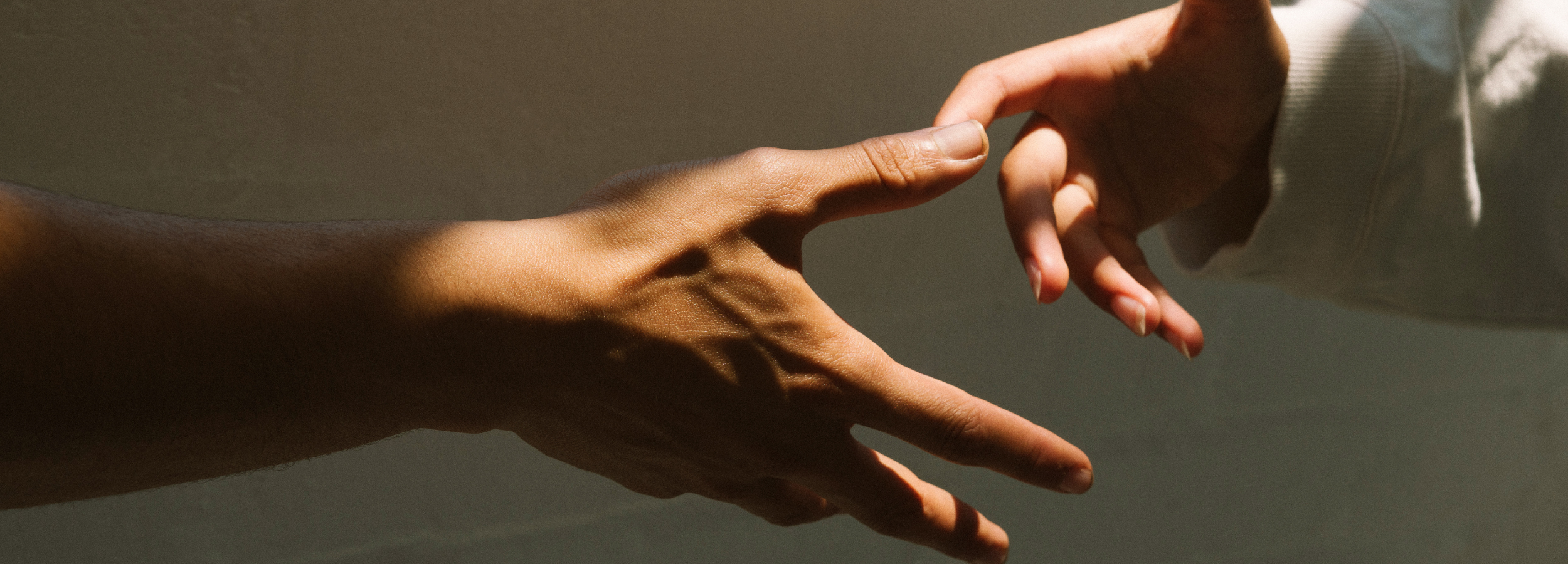 Two hands reaching towards each other against a neutral background — symbolizing Joreen Brands’ commitment to community, connection, and ethically sourced natural products.
